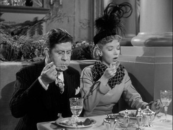 Movie still from “Unfaithfully Yours” (1948), directed by Preston Sturges – A man and a woman sitting at a dinner table; Medium shot, High angle