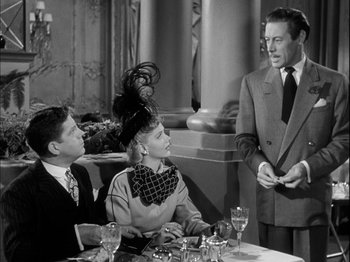 Movie still from “Unfaithfully Yours” (1948), directed by Preston Sturges – A group of people sitting around a table; Medium shot, Over the shoulder angle