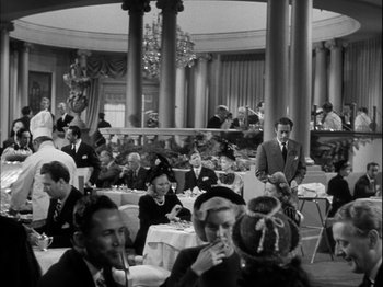 Movie still from “Unfaithfully Yours” (1948), directed by Preston Sturges – A black and white photo of people sitting at tables in a restaurant; Wide shot, High angle