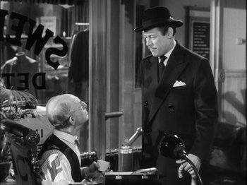 Movie still from “Unfaithfully Yours” (1948), directed by Preston Sturges – A man wearing a hat and a suit talking to another man in a hat; Medium shot, Over the shoulder angle