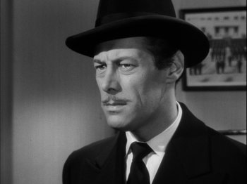 Movie still from “Unfaithfully Yours” (1948), directed by Preston Sturges – A black and white photo of a man wearing a suit and a hat; Close Up shot, Low angle