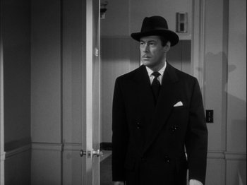 Movie still from “Unfaithfully Yours” (1948), directed by Preston Sturges – A black and white photo of a man in a suit and hat; Medium shot, Over the shoulder angle