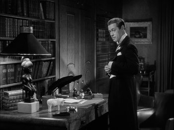 Movie still from “Unfaithfully Yours” (1948), directed by Preston Sturges – A black and white photo of a man standing in front of a desk; Medium shot, Low angle