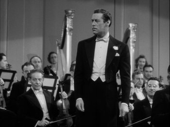 Movie still from “Unfaithfully Yours” (1948), directed by Preston Sturges – A black and white photo of a man in a tuxedo and bow tie; Medium shot, Over the shoulder angle