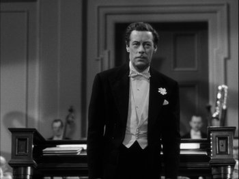 Movie still from “Unfaithfully Yours” (1948), directed by Preston Sturges – A man in a tuxedo standing in front of a courtroom; Medium shot, Low angle