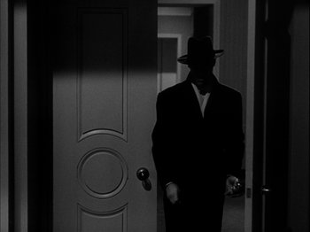 Movie still from “Unfaithfully Yours” (1948), directed by Preston Sturges – A man in a suit and hat standing in front of an open door; Medium shot, Over the shoulder angle