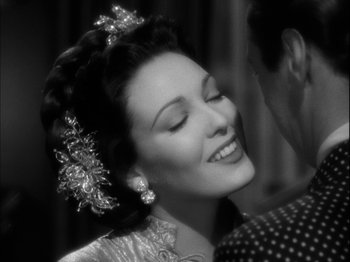 Movie still from “Unfaithfully Yours” (1948), directed by Preston Sturges – An old photo of a woman with a flower in her hair; Close Up shot, Over the shoulder angle