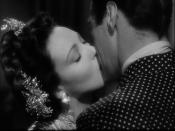 Movie still from “Unfaithfully Yours” (1948), directed by Preston Sturges – A man and a woman kissing each other in a black and white photo; Close Up shot, Over the shoulder angle