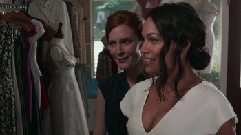 Movie still from “Unforgettable” (2017), directed by Denise Di Novi – Two women are posing for a picture in front of a dress; Close Up shot, Over the shoulder angle