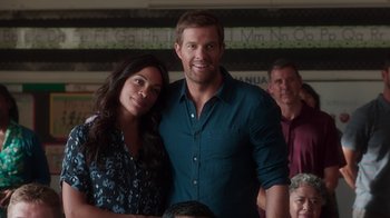 Movie still from “Unforgettable” (2017), directed by Denise Di Novi – A man and a woman posing for a picture in front of a crowd; Medium shot, Over the shoulder angle