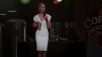 Movie still from “Unforgettable” (2017), directed by Denise Di Novi – A woman in a white dress is holding a microphone; Medium shot, Low angle