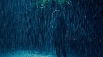Movie still from “Unforgettable” (2017), directed by Denise Di Novi – A person standing in the rain under an umbrella; Wide shot, High angle