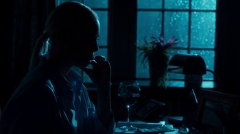 Movie still from “Unforgettable” (2017), directed by Denise Di Novi – A woman sitting at a table with a glass of wine; Medium shot, Low angle