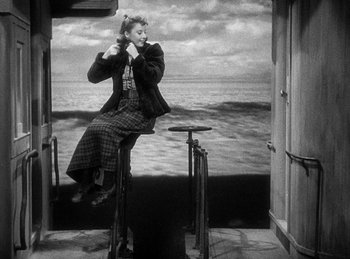 Movie still from “Union Pacific” (1939), directed by Cecil B. DeMille – A black and white photo of a woman sitting on a chair; Wide shot, High angle
