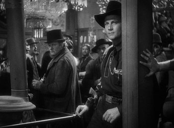 Movie still from “Union Pacific” (1939), directed by Cecil B. DeMille – Black and white photograph of a man in a cowboy hat; Medium shot, Over the shoulder angle