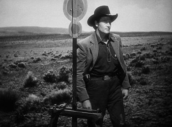 Movie still from “Union Pacific” (1939), directed by Cecil B. DeMille – A man in a cowboy hat standing next to a target; Medium shot, Low angle