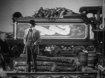 Movie still from “Union Pacific” (1939), directed by Cecil B. DeMille – A black and white photo of a man standing on a train track; Wide shot, Low angle