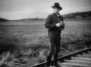 Movie still from “Union Pacific” (1939), directed by Cecil B. DeMille – A man standing on a train track holding a camera; Medium shot, Low angle