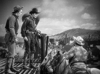 Movie still from “Union Pacific” (1939), directed by Cecil B. DeMille – Two men in cowboy hats standing next to horses; Wide shot, Low angle