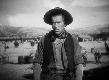 Movie still from “Union Pacific” (1939), directed by Cecil B. DeMille – A man wearing a cowboy hat standing in the middle of a field; Medium shot, Low angle