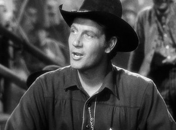 Movie still from “Union Pacific” (1939), directed by Cecil B. DeMille – A black and white photo of a man wearing a cowboy hat; Close Up shot, Over the shoulder angle