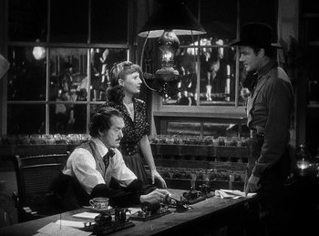 Movie still from “Union Pacific” (1939), directed by Cecil B. DeMille – A man and two women standing in front of a table; Medium shot, Over the shoulder angle