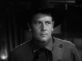 Movie still from “Union Pacific” (1939), directed by Cecil B. DeMille – A black and white photo of a man wearing a cowboy hat; Close Up shot, Over the shoulder angle