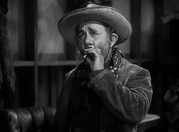 Movie still from “Union Pacific” (1939), directed by Cecil B. DeMille – A man in a cowboy hat smoking a cigarette; Close Up shot, Low angle