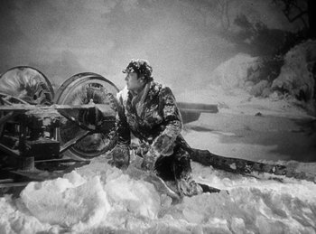 Movie still from “Union Pacific” (1939), directed by Cecil B. DeMille – A man kneeling in the snow next to an airplane; Wide shot, High angle