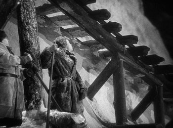 Movie still from “Union Pacific” (1939), directed by Cecil B. DeMille – A person wearing a coat and holding a pole; Wide shot, Low angle