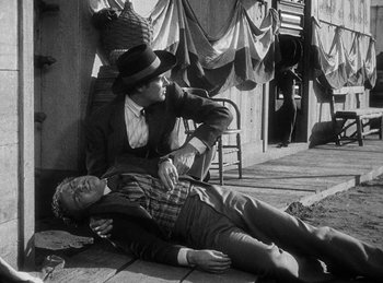 Movie still from “Union Pacific” (1939), directed by Cecil B. DeMille – A man laying on the ground next to another man on the ground; Medium shot, High angle