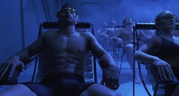 Movie still from “Universal Soldier: The Return” (1999), directed by Mic Rodgers – A man with no shirt is sitting in a steam room; Wide shot, High angle