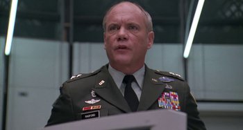 Movie still from “Universal Soldier: The Return” (1999), directed by Mic Rodgers – A man in a military uniform standing in front of a microphone; Close Up shot, Low angle