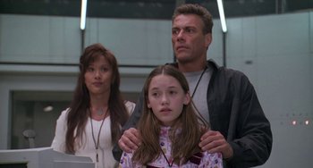 Movie still from “Universal Soldier: The Return” (1999), directed by Mic Rodgers – A man and a woman standing next to a young girl; Medium shot, Low angle