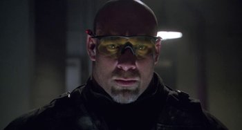 Movie still from “Universal Soldier: The Return” (1999), directed by Mic Rodgers – A bald man wearing goggles and a black jacket; Close Up shot, Low angle