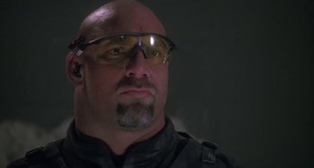 Movie still from “Universal Soldier: The Return” (1999), directed by Mic Rodgers – A bald man wearing glasses and a black jacket; Close Up shot, Low angle