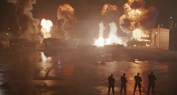 Movie still from “Universal Soldier: The Return” (1999), directed by Mic Rodgers – Three people standing in front of a large fire; Wide shot, Low angle