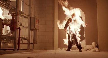 Movie still from “Universal Soldier: The Return” (1999), directed by Mic Rodgers – A man in a black jacket is in a fire pit; Medium shot, High angle