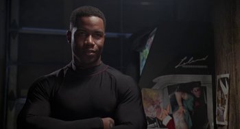 Movie still from “Universal Soldier: The Return” (1999), directed by Mic Rodgers – A man standing in front of some paintings; Close Up shot, Low angle