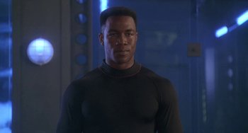 Movie still from “Universal Soldier: The Return” (1999), directed by Mic Rodgers – A man in a black shirt is looking at the camera; Close Up shot, Low angle