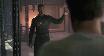 Movie still from “Universal Soldier: The Return” (1999), directed by Mic Rodgers – A man in a black outfit pointing at something; Medium shot, Over the shoulder angle