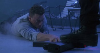 Movie still from “Universal Soldier: The Return” (1999), directed by Mic Rodgers – A man laying on the ground looking down at something; Medium shot, High angle
