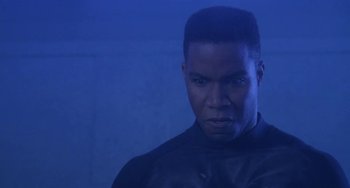 Movie still from “Universal Soldier: The Return” (1999), directed by Mic Rodgers – A man in a black jacket is looking at the camera; Close Up shot, Low angle