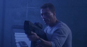 Movie still from “Universal Soldier: The Return” (1999), directed by Mic Rodgers – A man is holding a gun in a room; Medium shot, Low angle