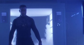Movie still from “Universal Soldier: The Return” (1999), directed by Mic Rodgers – A man standing in front of a door in a room; Medium shot, Low angle