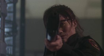 Movie still from “Universal Soldier: The Return” (1999), directed by Mic Rodgers – A man holding a gun while wearing glasses; Close Up shot, Low angle
