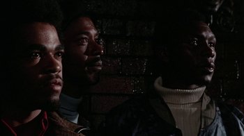 Movie still from “Uptight” (1968), directed by Jules Dassin – A group of men standing next to each other in front of a brick wall; Close Up shot, Low angle