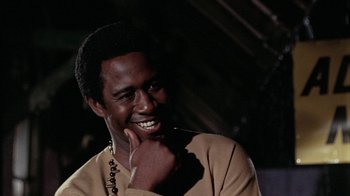 Movie still from “Uptight” (1968), directed by Jules Dassin – A man smiles while holding his hand under his chin; Close Up shot, Over the shoulder angle
