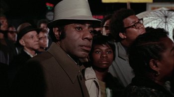 Movie still from “Uptight” (1968), directed by Jules Dassin – A group of people standing in front of a crowd; Close Up shot, Low angle