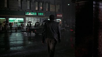 Movie still from “Uptight” (1968), directed by Jules Dassin – A man walking down a street in the rain; Wide shot, Low angle